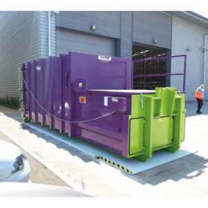 The portable Model L Roro compactor in purple and green outside a warehouse.